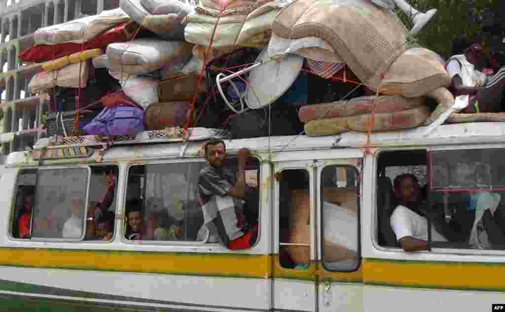 Yemenis sit aboard a bus loaded with belongings of the people fleeing the ongoing fighting between militiamen loyal to Saudi-backed fugitive President Abderabbo Mansour Hadi and Iran-backed Shiite Huthi rebels in the port city of Aden.