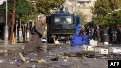 An Iraqi man crosses a street past security forces during clashes in Sulaimaniyah, in Iraq's Kurdistan region, on Oct. 10, 2015.