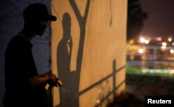 A Brazilian drug gang member poses with a gun in a slum in Rio de Janeiro, Brazil, March 17, 2018.