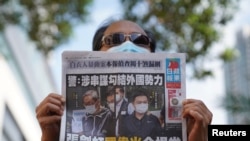 FILE - A supporter holds a copy of Apple Daily newspaper during a court hearing outside West Magistrates’ Courts, after police charge two executives of the pro-democracy Apple Daily newspaper over the national security law, in Hong Kong, China, June 19, 2021. (Reuters)