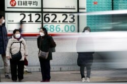 Pedestrians stand in front of an electronic stock board showing Japan's Nikkei 225 index at a securities firm in Tokyo Friday, Feb. 28, 2020. Asian stock markets have fallen further on virus fears after Wall Street endured its drop