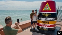 Norwegians Marthe and Erling Bakkemo have their photo taken by the Southernmost Point marker in Key West, Fla., Oct. 27, 2017. The tourist icon was repaired and repainted after it was damaged by Hurricane Irma. Tropical Storm Philippe was to reach the Keys Saturday night.