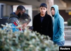 FILE - Two members a group of unaccompanied minors (R and 2nd R) from the Jungle migrant camp in Calais stand outside an immigration centre after being processed after their arrival in Britain, in Croydon, south London, Oct. 18, 2016.