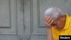 A pensioner waits in front of the main entrance of a National Bank branch to receive part of his pension in central Athens, July 9, 2015. 