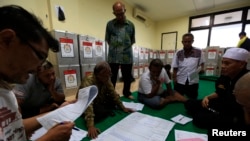 Election commission official Dedi Saidi, left, reads document stating the number of votes collected in ballot boxes, Bendungan Hilir, Jakarta, July 10, 2014.