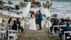 This photo shows bride Namisha Balagopal and groom Suhaas Prasad getting married in a small legal ceremony Aug. 15, 2020, on Muir Beach near San Francisco. The couple plans a larger traditional South Asian Indian wedding this August in Utah. (Vellora Productions via AP)