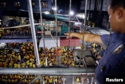 FILE - A guard points at inmates gathered at the basketball court for a head count before going to sleep at Quezon City Jail in Manila, Philippines, Oct. 18, 2016.