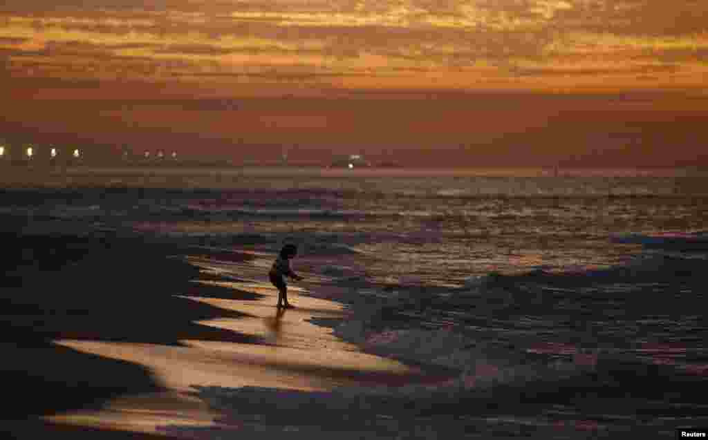 A Palestinian girl plays on the beach of Gaza City after sunset.