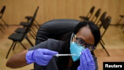 Un trabajador de la salud prepara dosis de la vacuna contra el covid, en el Acres Home Multi-Service Center, en Houston, Texas, EE. UU., el 13 octubre de 2021.