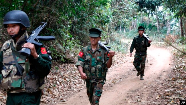 ນັກລົບກອງທັບເອກະລາດກະຈິນພາກັນຍ່າງຈາກສະໜາມລົບຢູ່ແນວໜ້າໃນເມືອງ ມູດູ ໄປຫາຖານທັບຜາລັບ ຢູ່ໃນເຂດທີ່ຄວບຄຸມໂດຍພວກກະບົດຊາວກະຈິນ ໃນເຂດເໜືອຂອງມຽນມາ ໃນວັນທີ 17 ມີນາ, 2018