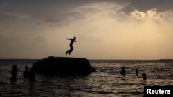 FILE - A boy prepares to jump off a rock into the waters of the Osman Sagar Lake near the southern Indian city of Hyderabad, May 29, 2011.