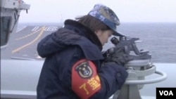 中國遼寧號航空母艦星期四駛過台灣海峽,一名女官兵視察海面情況。。(視頻截圖)