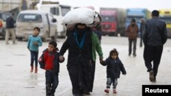 Internally displaced Syrians carry their belongings as they arrive at a refugee camp near the Bab al-Salam crossing, across from Turkey's Kilis province, on the outskirts of the northern border town of Azaz, Syria, Feb. 6, 2016. 