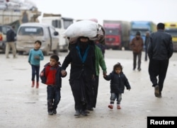 FILE - Internally displaced Syrians carry their belongings as they arrive at a refugee camp near the Bab al-Salam crossing, across from Turkey's Kilis province, on the outskirts of the northern border town of Azaz, Syria, Feb. 6, 2016.