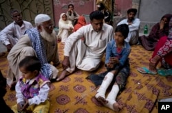 Fahd Ali, 10, right, who was injured in a bombing that killed his parents and sister and wounded two sisters, narrates his ordeal to visitors outside his home in Lahore, Pakistan, March 28, 2016.