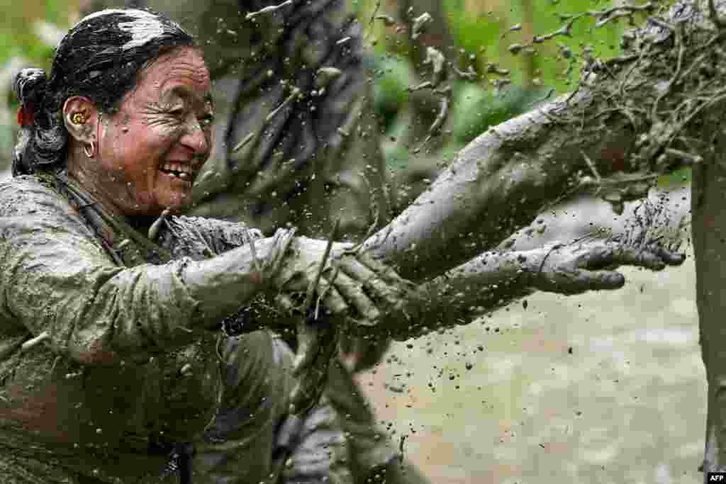 Mud-covered farmers play in a rice paddy field during &quot;National Paddy Day&quot;, which marks the start of the yearly rice planting season, in Tokha village, Nepal.