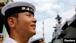 FILE - A member of Japan's Maritime Self-Defense Force looks at its new helicopter destroyer DDH183 Izumo, the largest surface combatants of the Japanese navy, before its launching ceremony in Yokohama, south of Tokyo, Aug. 6, 2013.
