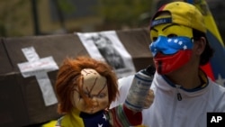 A protester with a Guy Fawkes mask, painted with the Venezuelan flag colors, carries a doll with a tear gas canister during a march in Caracas April 15, 2014.