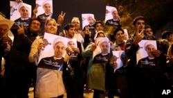 In this photo released by the Iranian Students News Agency, ISNA, Iranians hold posters of President Hassan Rouhani as they welcome Iranian nuclear negotiators upon their arrival from Geneva at the Mehrabad airport in Tehran, Nov. 24, 2013. 