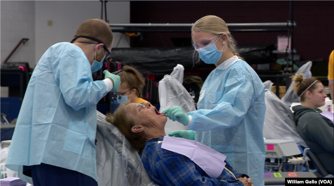 Two volunteer dentists work with a patient at the RAM Clinic, a free mobile health center set up in a school in Charleston, WV. Saturday, Oct. 20, 2018.