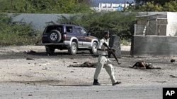 Somali police officers walk past bodies of two civilians who were killed during a suicide-bomb attack targeting Mogadishu international airport, 09 Sep 2010