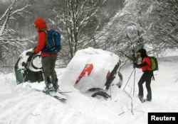 Members of Lazio's Alpine and Speleological Rescue Team are seen next to cars covered in snow in front of the Hotel Rigopiano in Farindola, Italy, that was hit by an avalanche, Jan. 19, 2017.