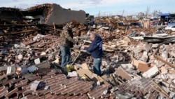 Men sort through a destroyed business Saturday, Dec. 11, 2021, in Mayfield, Ky. (AP Photo/Mark Humphrey)