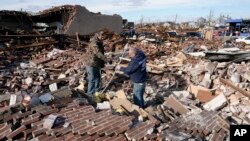 Men sort through a destroyed business Saturday, Dec. 11, 2021, in Mayfield, Ky. (AP Photo/Mark Humphrey)