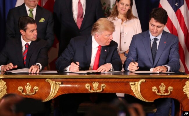 FILE - President Trump, looks over at Canada's Prime Minister Justin Trudeau's document as they and Mexico's President Enrique Pena Nieto sign a new United States-Mexico-Canada Agreement that replaces the NAFTA trade deal.
