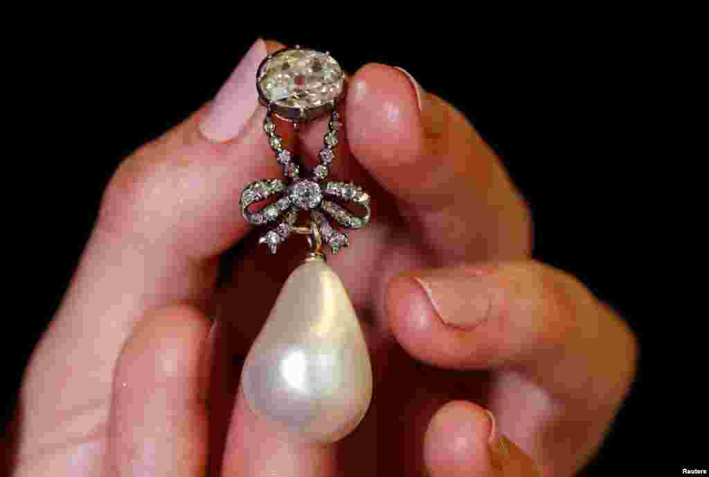 A natural pearl and diamond pendant once owned by Marie Antoinette is held by a model during a press preview ahead of the upcoming auction &quot;Royal jewels from the Bourbon Parma Family&quot; at Sotheby&#39;s in Geneva, Switzerland.