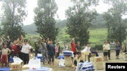 A handout photo dated July 31, 2012 shows North Korean residents waving as they receive relief goods from DPRK Red Cross Society (RCS) after rain-triggered floods hit Songchon county, South Pyongan Province.