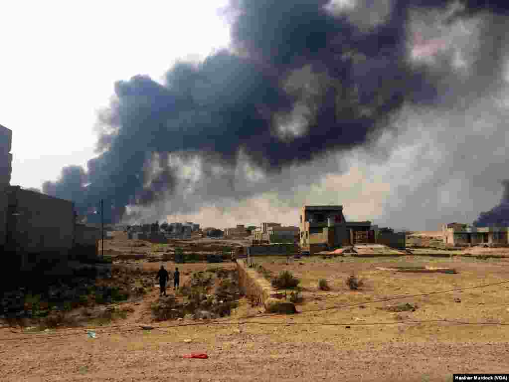 In Qayyarah, Iraq, smoke from burning oil wells burns over the city after being set on fire again by Islamic State militants. October 24, 2016. (H.Murdock/VOA)