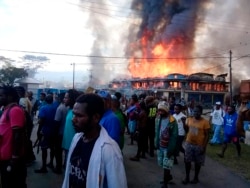 Orang-orang berkumpul saat toko-toko terbakar selama protes di Wamena di Papua, Senin, 23 September 2019. (Foto: AP)