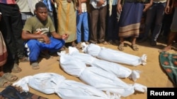 FILE - A man sits as others stand near the wrapped up bodies of children from the same family, one day after they were killed in a Saudi-led airstrike on their house in Bajil district of the Red Sea province of Houdieda, Yemen, Oct. 8, 2016. 
