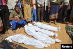 A man sits as others stand near the wrapped up bodies of children from the same family, one day after they were killed in a Saudi-led airstrike on their house in Bajil district of the Red Sea province of Houdieda, Yemen, Oct. 8, 2016.