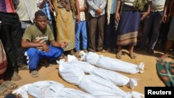 FILE - A man sits as others stand near the wrapped bodies of children from the same family, one day after they were killed in a Saudi-led airstrike on their house in Bajil district of the Red Sea province of Houdieda, Yemen, Oct. 8, 2016. 