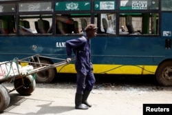 A man pulling a cart passes next to a bus vandalized during the latest protests in Mathare, Nairobi, Kenya, August 14, 2017.