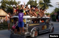 Warga naik di atap jeepney yang penuh sesak di jalan raya di Kota Mogpog, di Pulau Marinduque, Filipina tengah, 8 April 2015