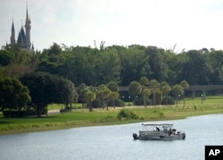 Orange County Sheriff's officers search the Seven Seas Lagoon between Walt Disney World's Magic Kingdom theme park, left, and the Grand Floridian Resort & Spa in Lake Buena Vista, Florida, June 15, 2016, after a two-year-old toddler was dragged into the lagoon by an alligator.