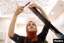 Huda Quhshi, owner and cosmetologist at the Le'Jemalik Salon and Boutique, cuts the hair of a customer ahead of the Eid al-Fitr Islamic holiday in Brooklyn, New York, June 21, 2017.