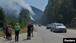 Tourists from Denmark stop to photograph one of several wildifres burning near Little Fort, British Columbia, Canada, July 9, 2017. 
