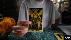 FILE - A fortune teller poses with tarot cards at a temple in Bangkok, Feb. 12, 2019.