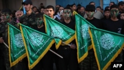 FILE - Palestinian youths hold Hamas movement flags during a rally near the Rafah border between southern Gaza Strip and Egypt on February 5, 2015.