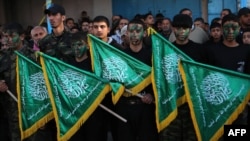 FILE - Palestinian youths hold Hamas movement flags.