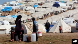 Syrian refugees filling their buckets at Atmeh refugee camp, in the northern Syrian province of Idlib, Syria, Apr. 5, 2013