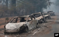 The burned out hulks of cars abandoned by their drivers sit along a road, Nov. 9, 2018, in Paradise, Calif.