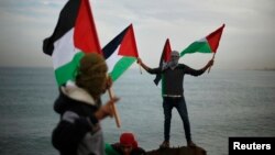 Palestinians wave national flags during a protest against the blockade on Gaza, at the seaport of Gaza City Dec. 2, 2013.
