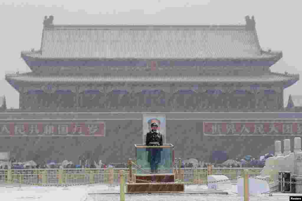 A paramilitary officer stands guard during a snowfall at the Tiananmen Square in Beijing, China.