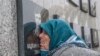 Kosovo Albanian woman Vezire Gjeladini, 76, kisses the picture of her son etched into a commemorative plaque and placed on a wall dedicated to the victims of the Racak massacre, on Jan. 15, 2018.