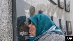 Kosovo Albanian woman Vezire Gjeladini, 76, kisses the picture of her son etched into a commemorative plaque and placed on a wall dedicated to the victims of the Racak massacre, on Jan. 15, 2018.